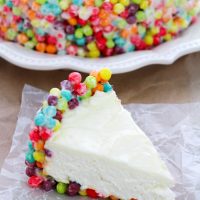 Slice of No-Bake Trix Cheesecake in the front and the rest of the cheesecake in the background.