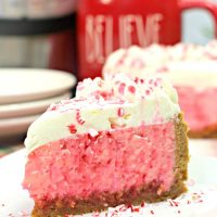 Slice of candy cane cheesecake on a white plate with red mug in the background along with an Instant Pot.