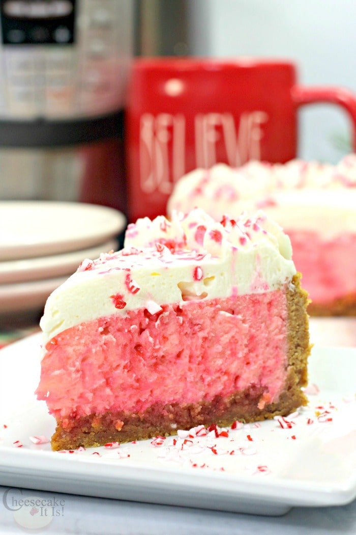Slice of peppermint cheesecake on a white plate with red mug in the background along with an Instant Pot.