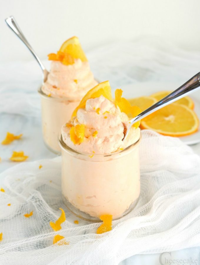 Two small glass jars full of keto orange cheesecake mousse with spoons in them.