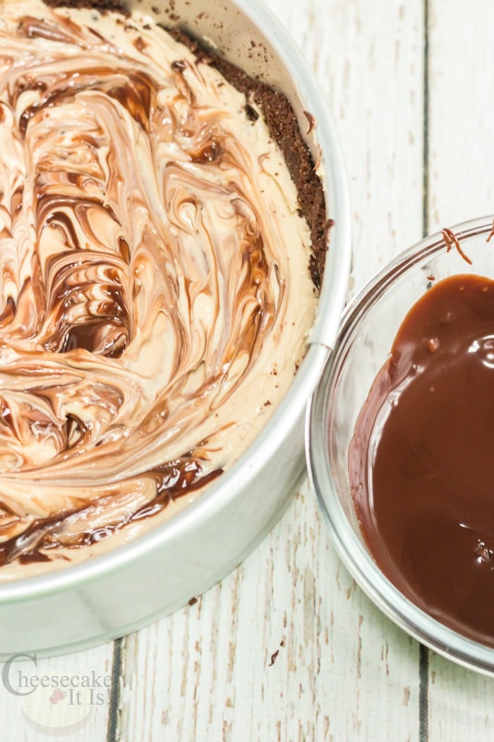 Cheesecake and chocolate being swirled in pan
