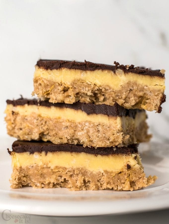 3 Peanut Butter & Chocolate Cheesecake Bars stacked on white plate
