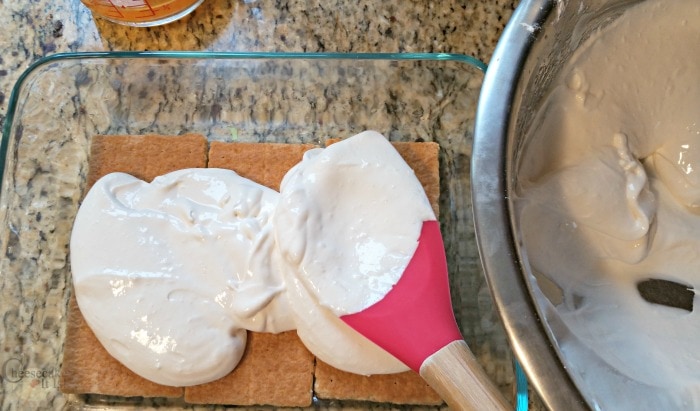 Spoon spreading cheesecake mixture over crackers