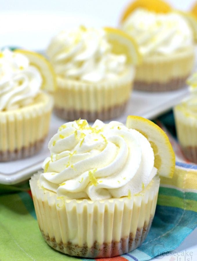 Lemon cheesecake minis in cupcake liners topped with whipped topping and lemon zest