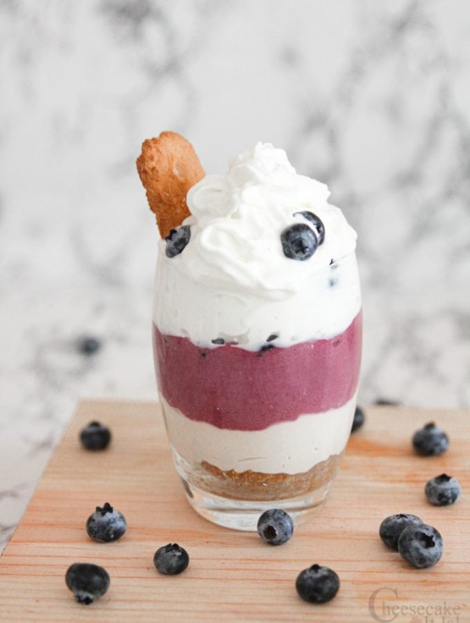 Finished no bake blueberry cheesecake in a glass topped with whipped topping and fresh blueberries