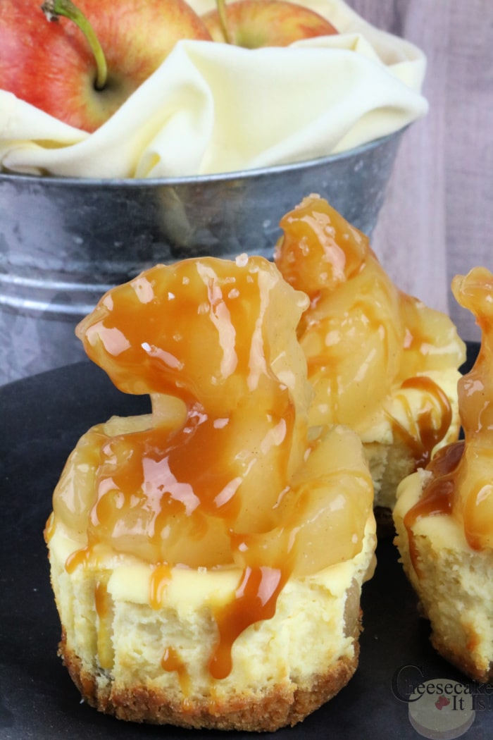 Finished mini caramel apple cheesecakes with apples in background