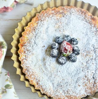 Whole Japanese cheesecake still in pan topped with powdered sugar and berries
