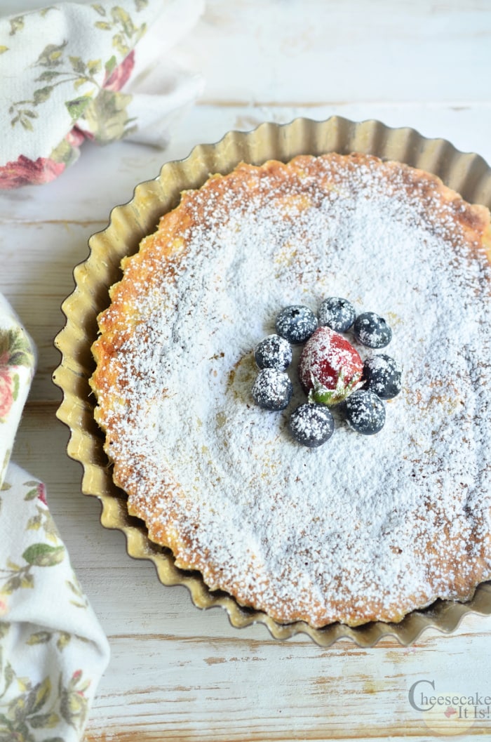 Whole Japanese cheesecake still in pan topped with powdered sugar and berries
