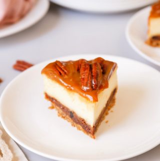 Slice of pecan pie cheesecake on white plate