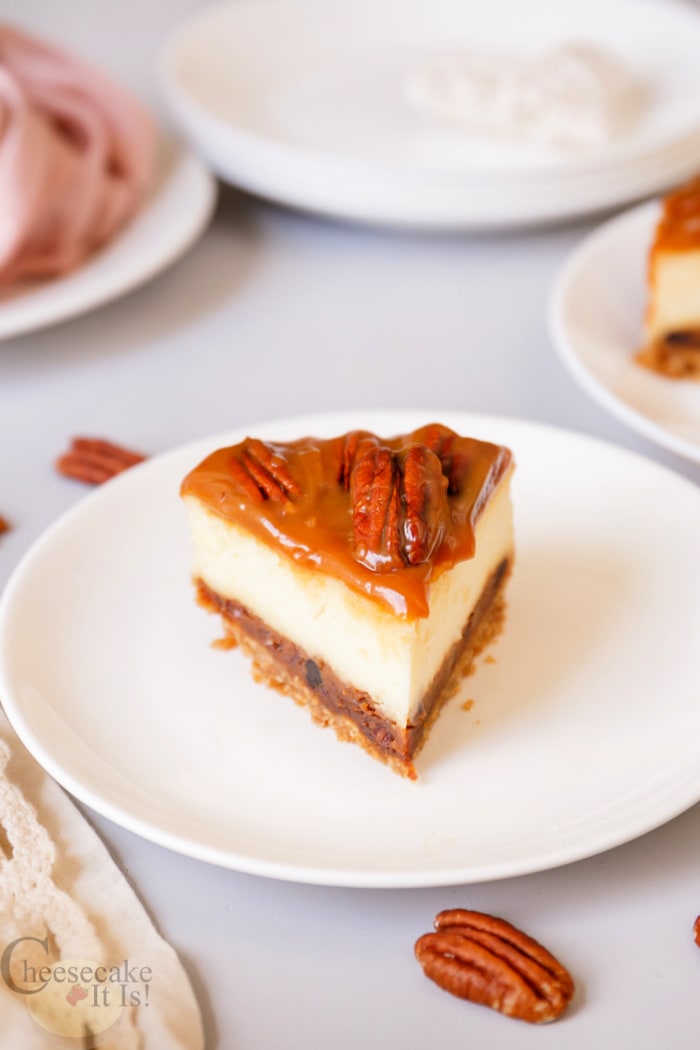 Slice of pecan pie cheesecake on white plate