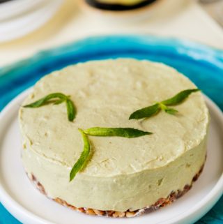 Whole avocado cheesecake on white plate with blue liner