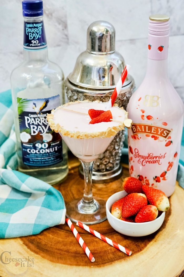 Full glass of strawberry shortcake martini with coconut rum and Baileys strawberries and cream behind