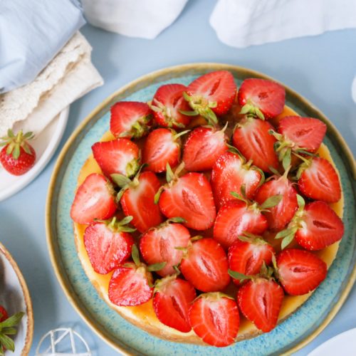 Whole strawberry cheesecake topped with fresh strawberries.