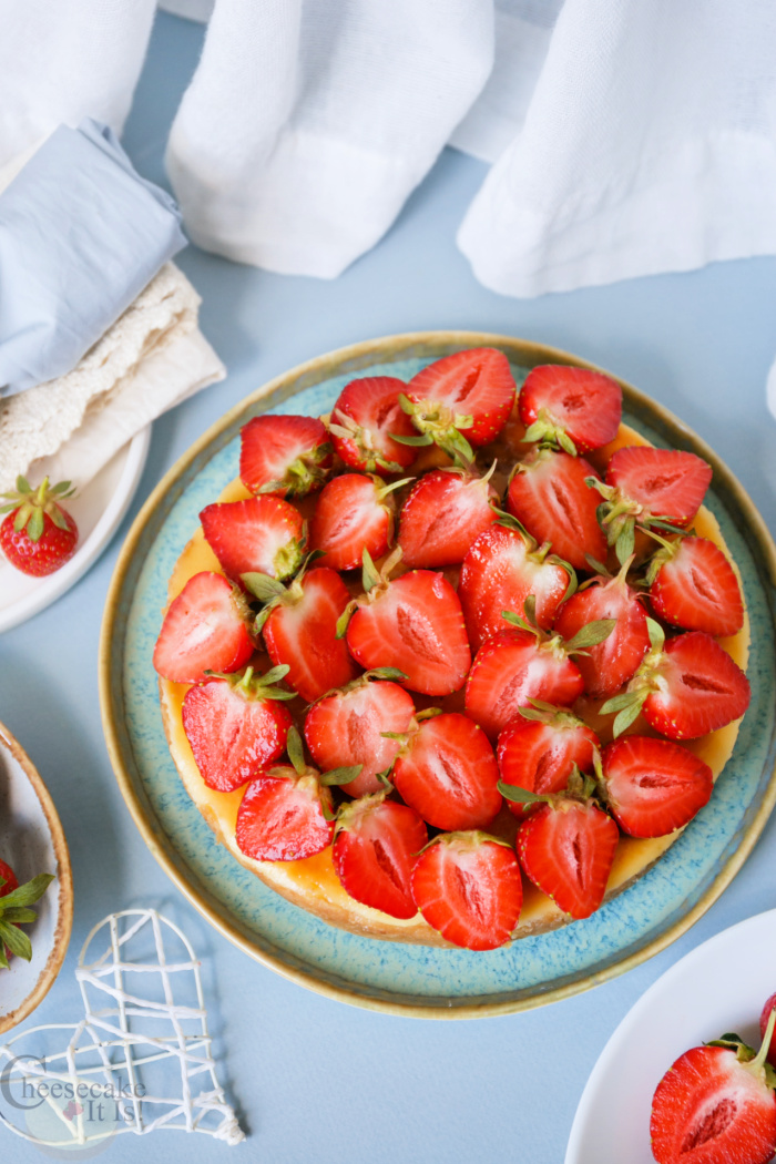 Whole strawberry cheesecake topped with fresh strawberries.