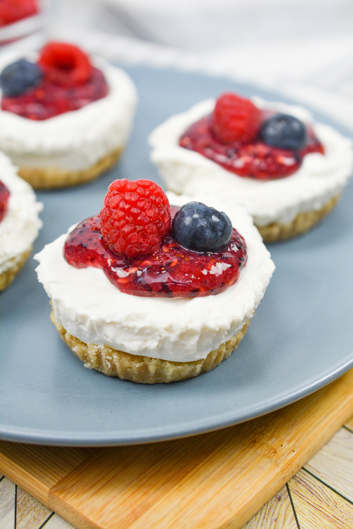 4 berry mini cheesecakes keto dessert with cream cheese sitting on a blue plate.