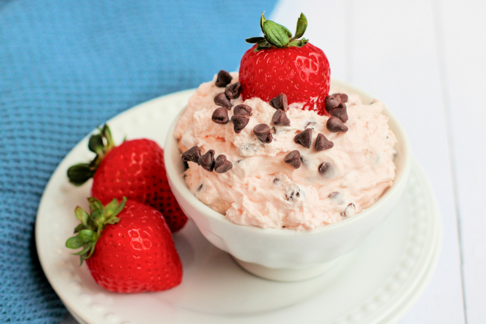 Cherry Chocolate Chip Cheesecake Dip in white bowl with a strawberry on the top and two to the side