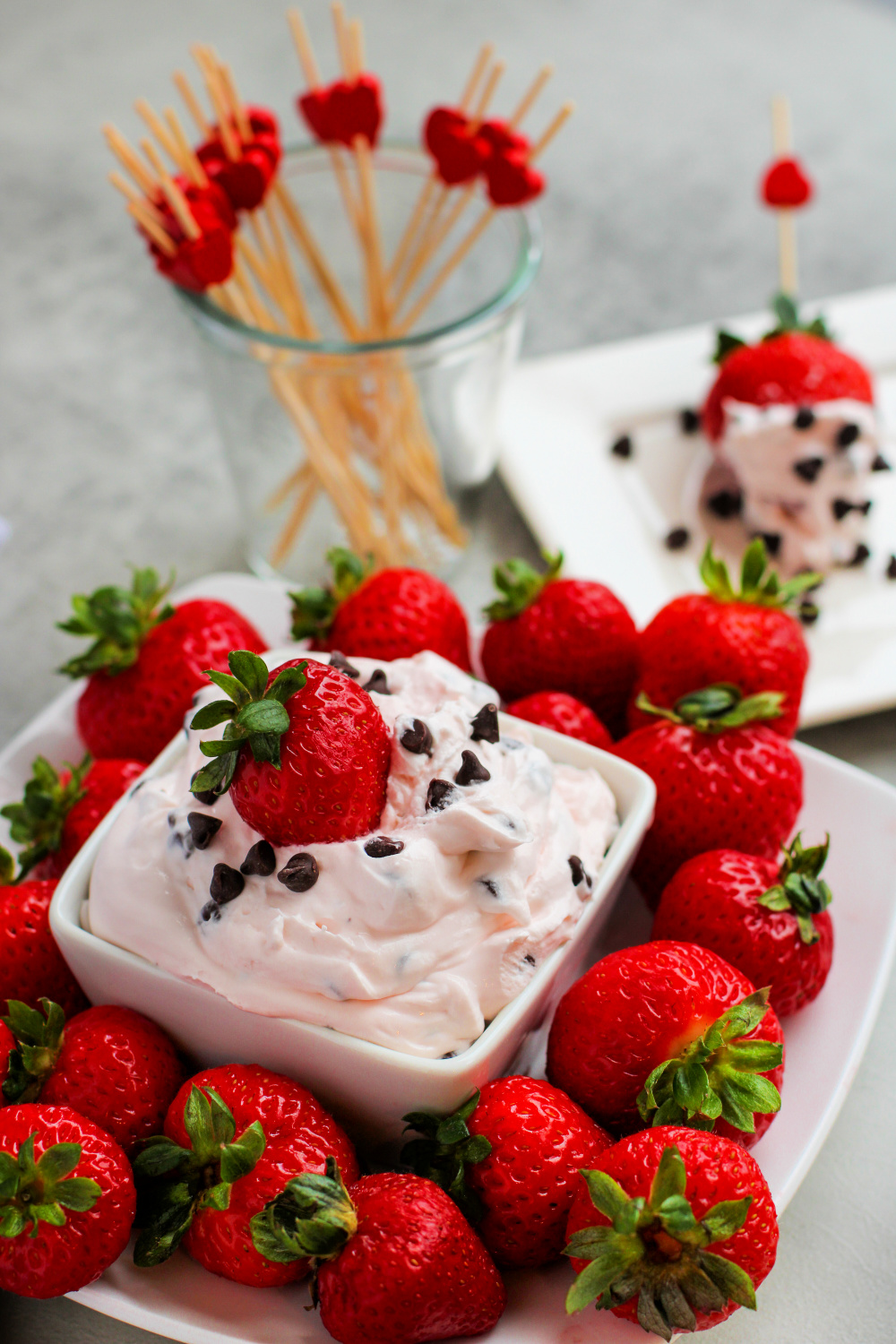 Small bowl of Cherry Chocolate Chip Cheesecake Dip with strawberries all the way around the bowl